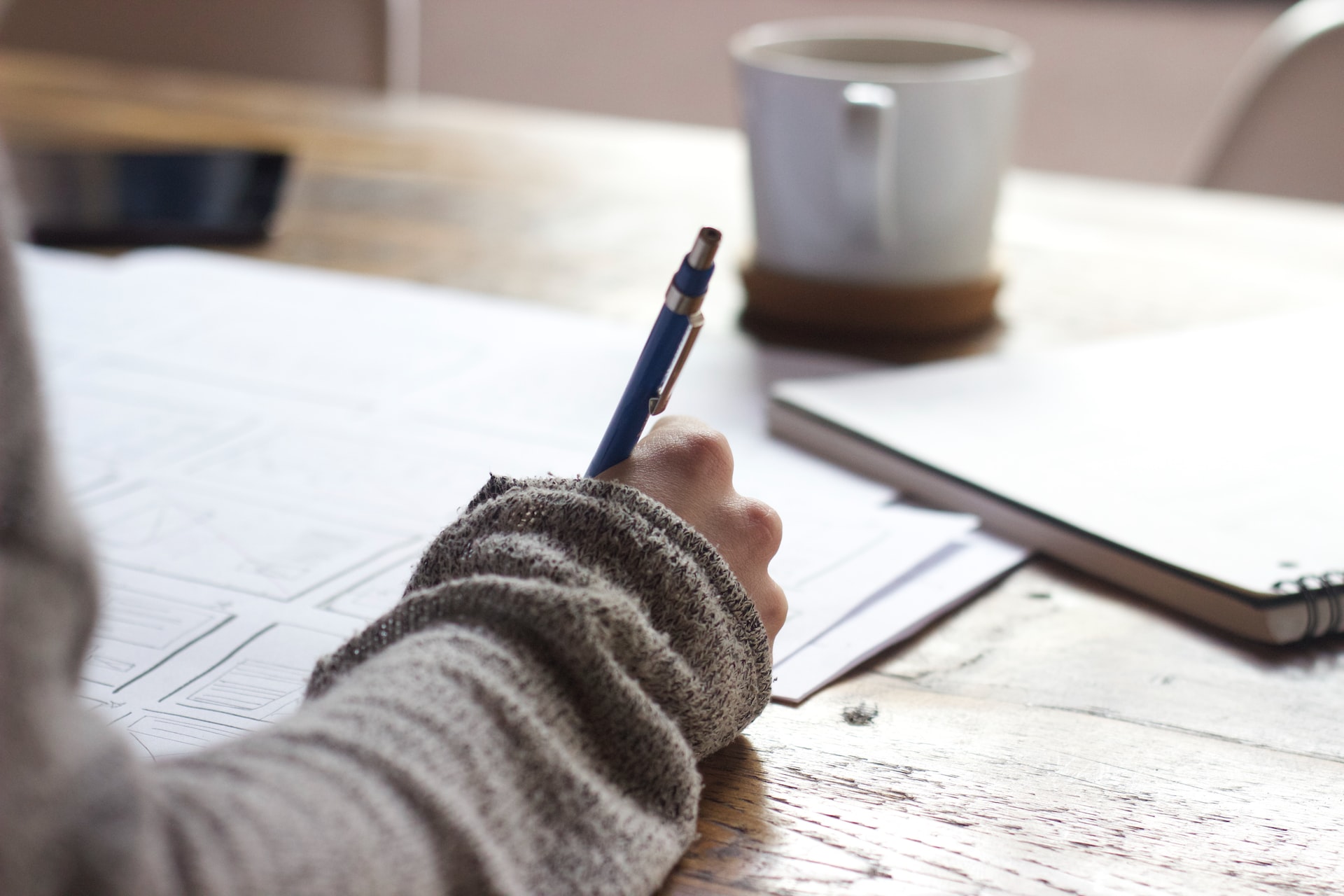 Person writing papers at desk