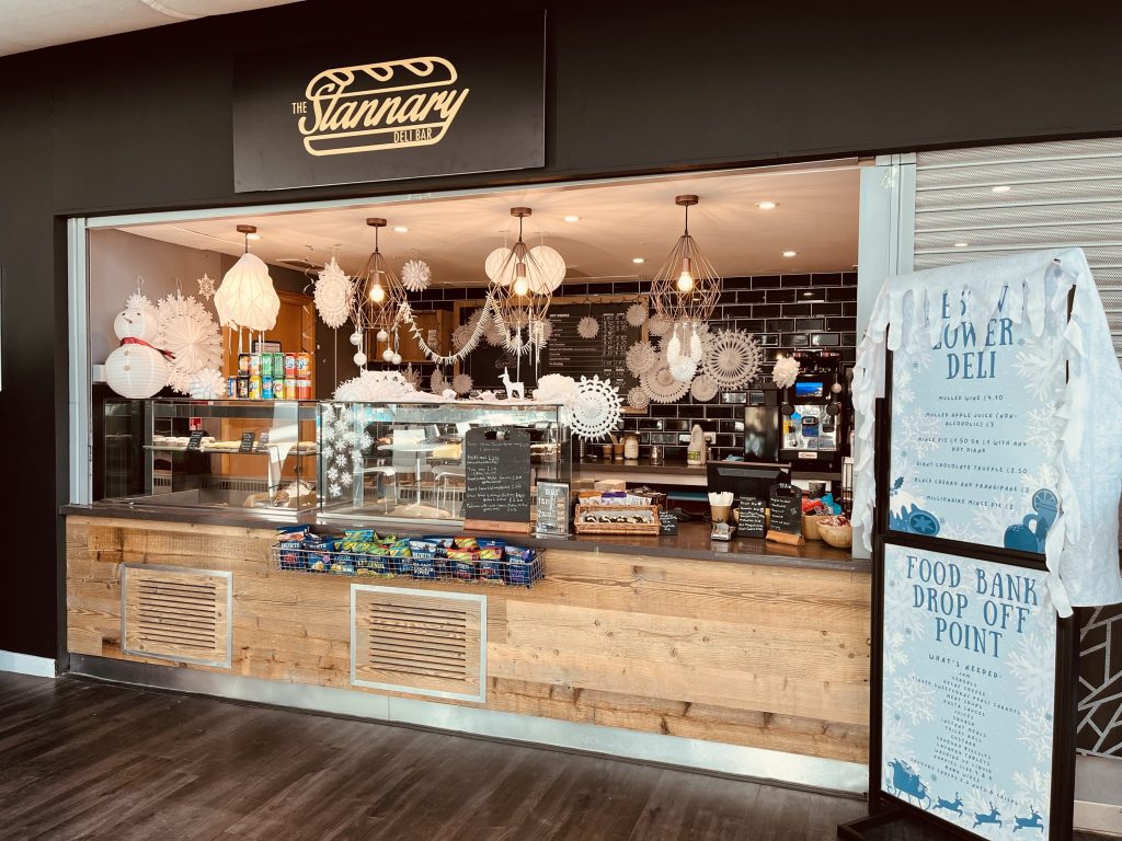 An image of the Stannary Deli Bar with festive decorations and the food bank drop off signage to the right hand side of the outlet.