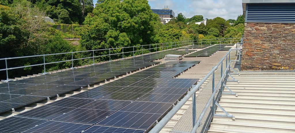 The PV panels pictured on the roof of the AMATA building, surrounded by trees with the Exchange campus building in the background.