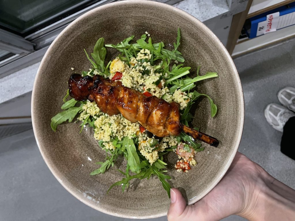 Image of a kebab on couscous and rocket, one of the mains plus two salad options at the ESI Cafe.