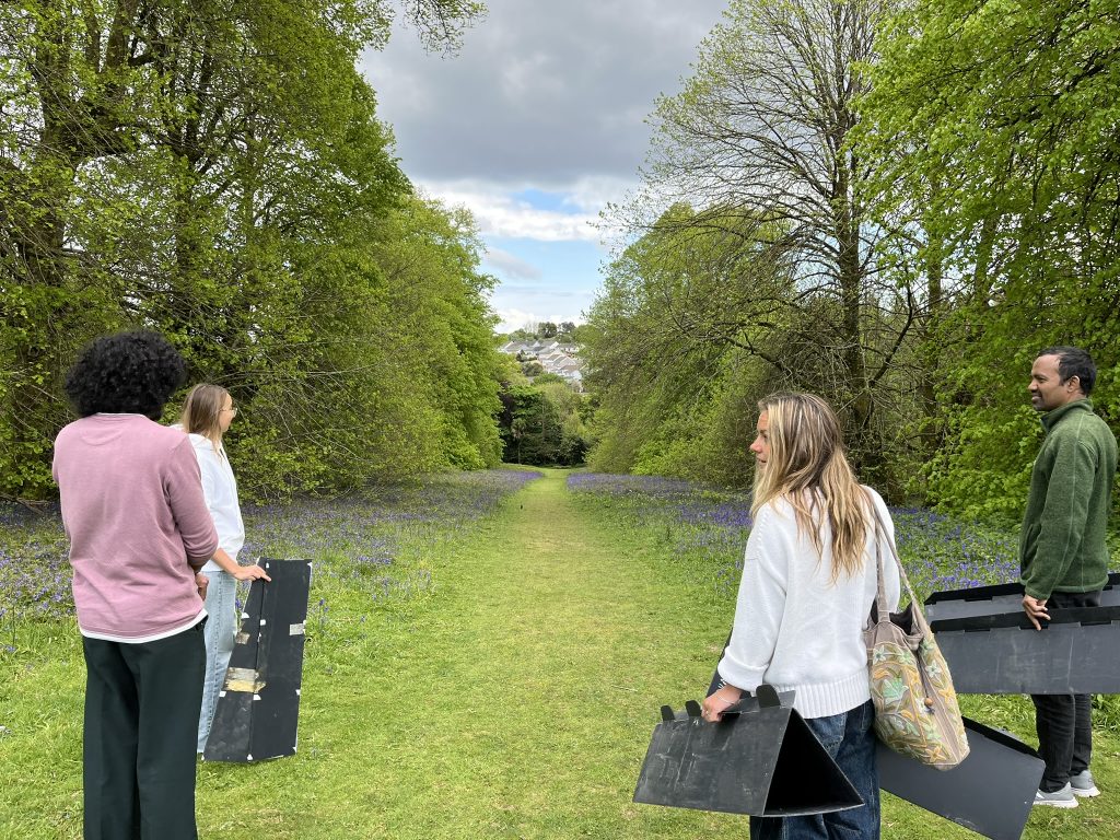 Students walking down Lime Avenue at Penryn campus, carrying hedgehog tunnels to track them.