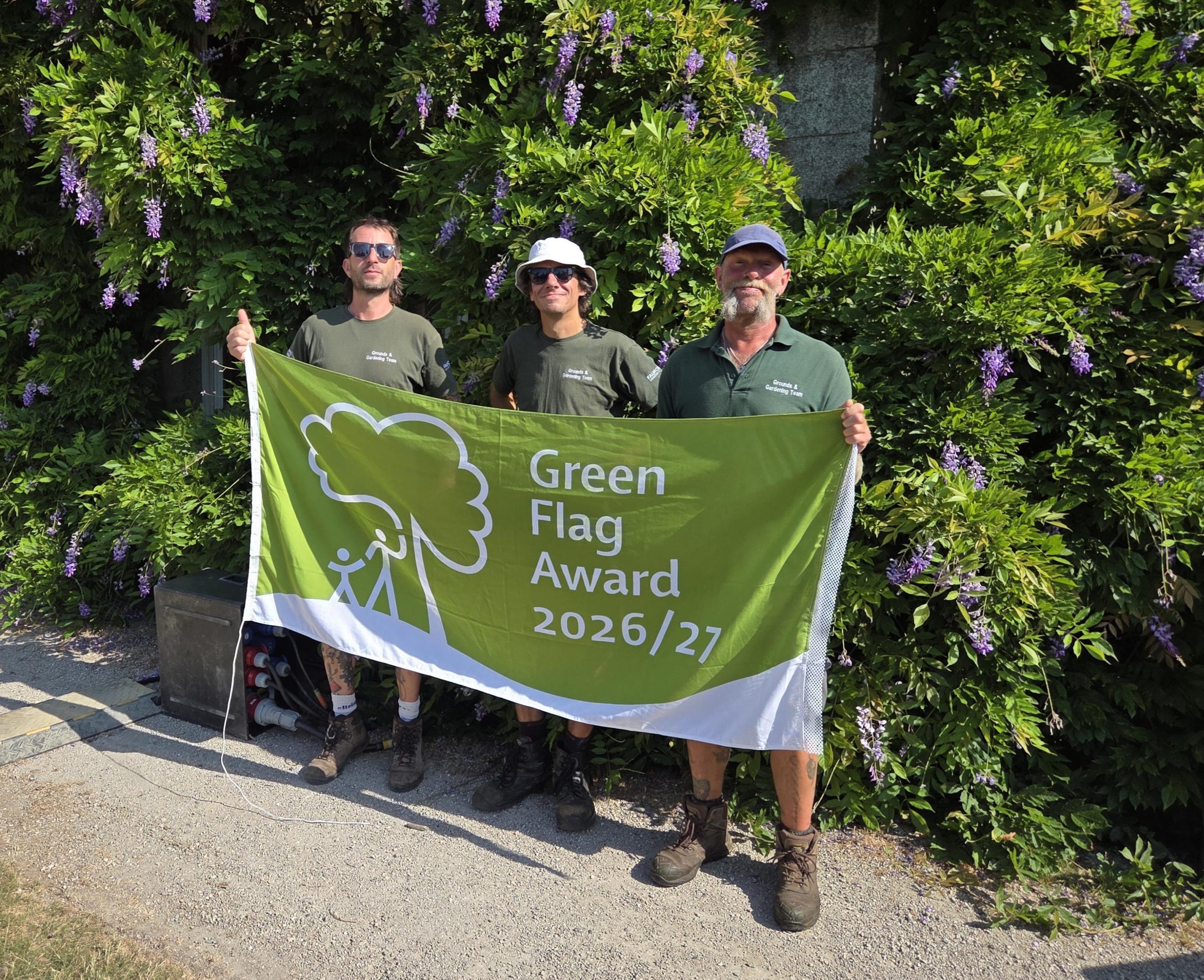 FX Plus Grounds and Garden team holding up the green flag award 2026/27